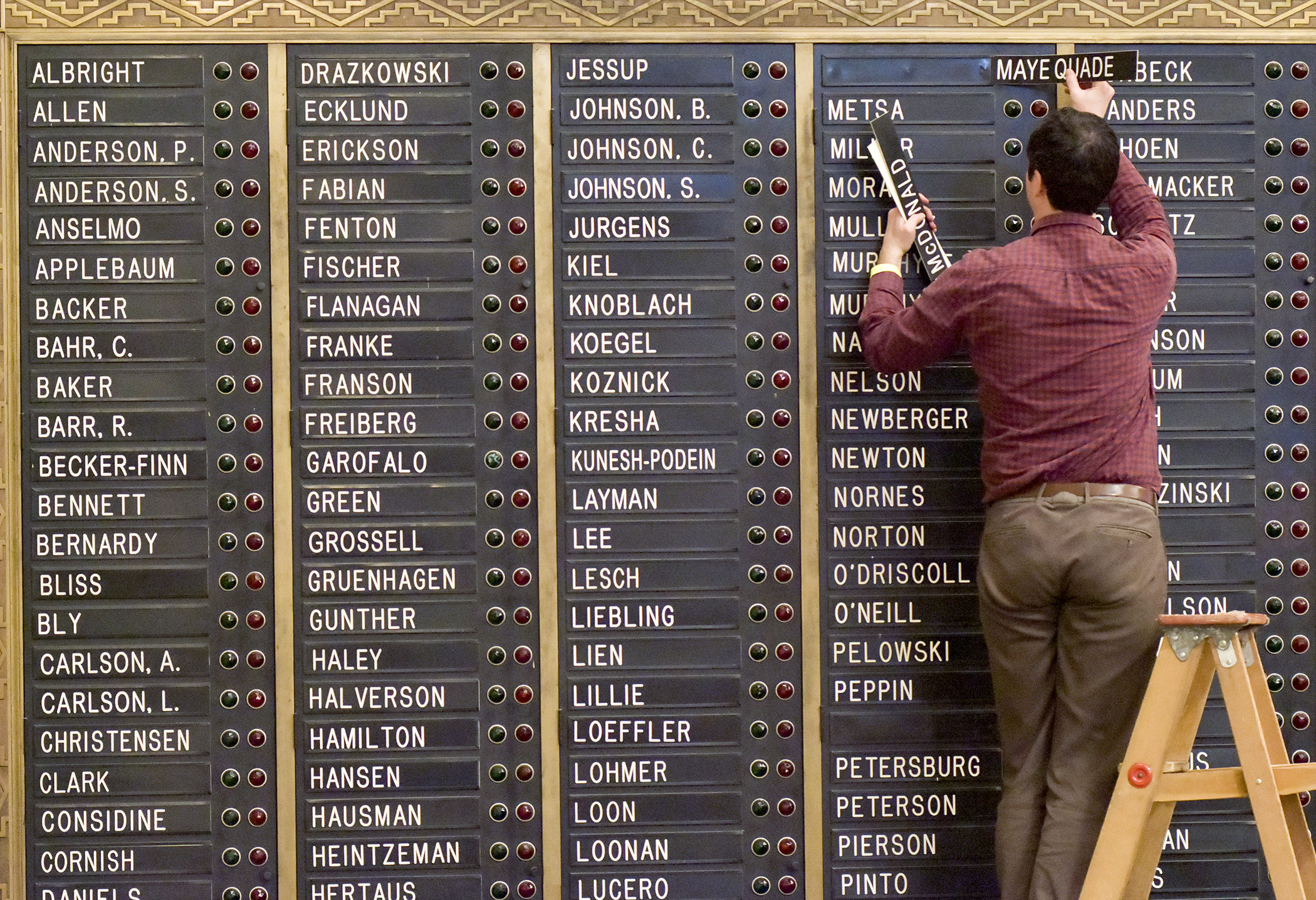 Assistant Desk Secretary Sean Kittridge adjusts member nameplates on the voting boards in the House Chamber Dec. 29 in preparation for Tuesday’s start of the 2017 legislative session. Photo by Andrew VonBank